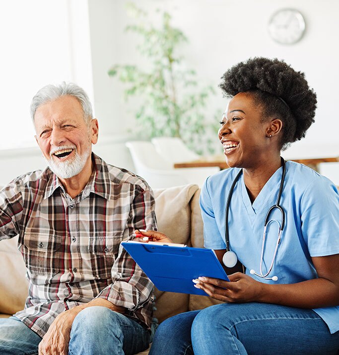 A smiling woman and an older man relax together on a cozy couch