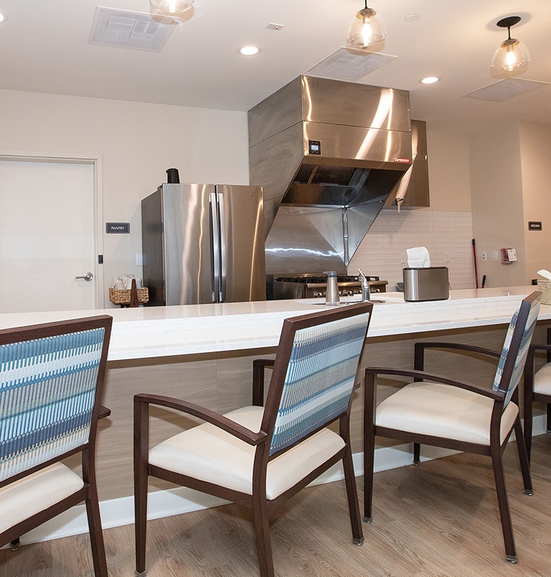 kitchen featuring a stove, refrigerator, and several chairs around a dining table.