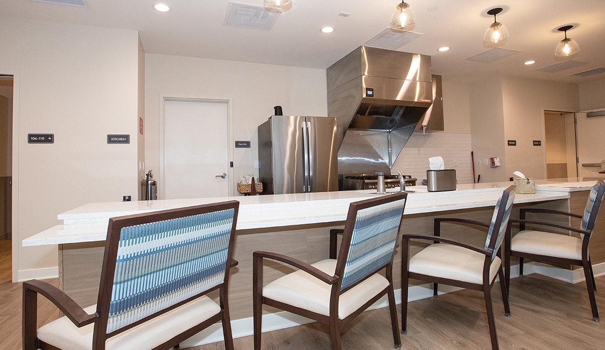 kitchen featuring a stove, refrigerator, and several chairs around a dining table.