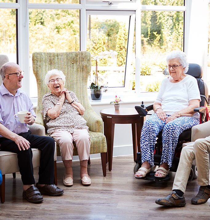A group of women gathered around a table, happily painting together with colorful supplies.